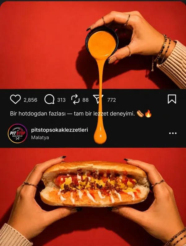 Kırmızı fonda iki elle tutulan hot dog
